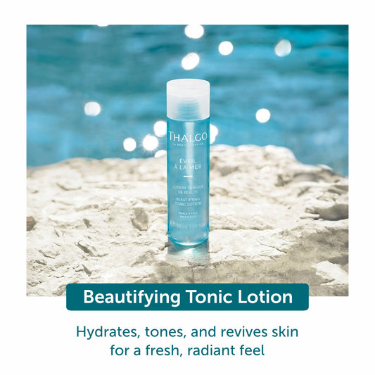 THALGO beautifying tonic lotion bottle, teal liquid, standing on light rocks
